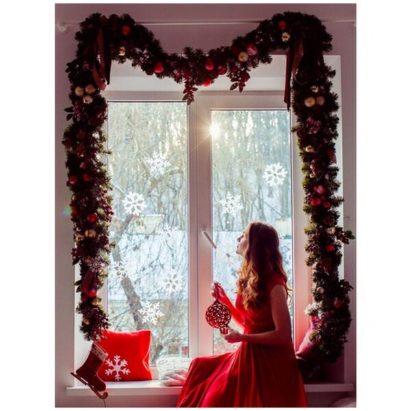 Lady in red dress sits on the widnowsill decorated with Christma